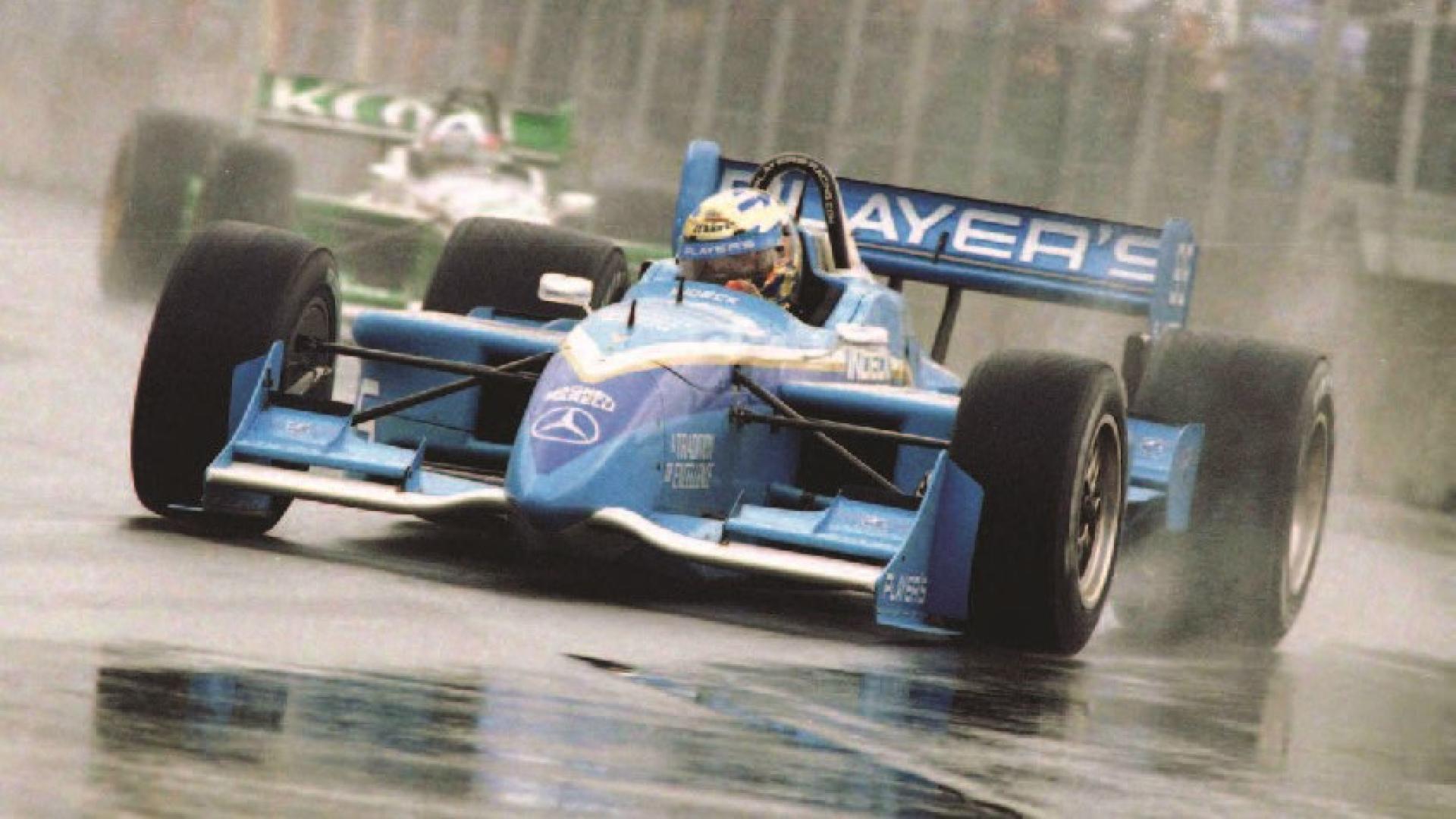 Greg Moore drives along a wet track in a race.